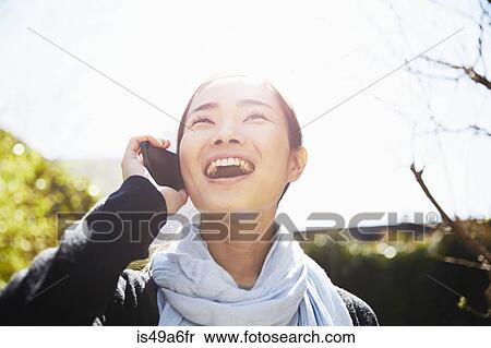 Stock Photography - Young woman on smartphone, laughing. Fotosearch
