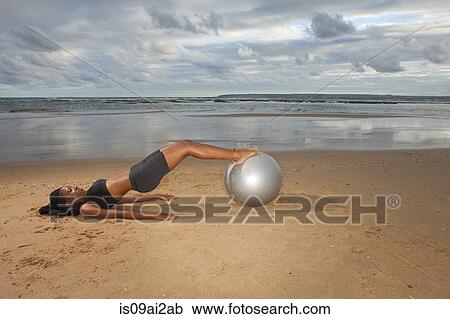 Young woman practicing yoga with exercise ball at beach View Large Photo Image Stock Image - Young woman practicing yoga with exercise ball at beach. Fotosearch