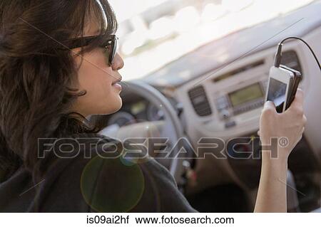 Young woman reading text on her cellphone in car View Large Photo Image Stock Image - Young woman reading text on her cellphone in car. Fotosearch