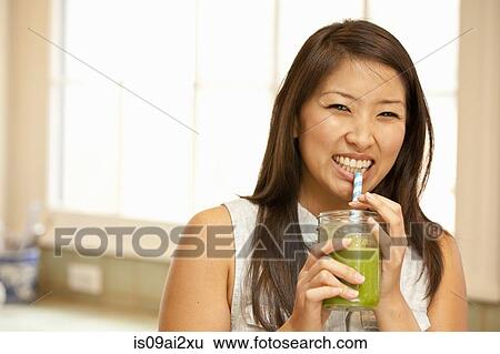 Young woman sipping green smoothie View Large Photo Image Stock Photograph - Young woman sipping green smoothie. Fotosearch