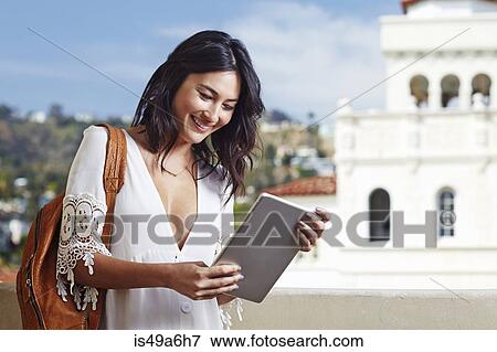 Young woman using digital tablet outdoors View Large Photo Image Stock Photo - Young woman using digital tablet outdoors. Fotosearch