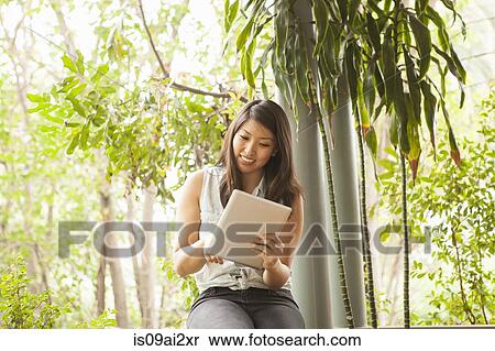 Stock Photography - Young woman using digital tablet outdoors. Fotosearch