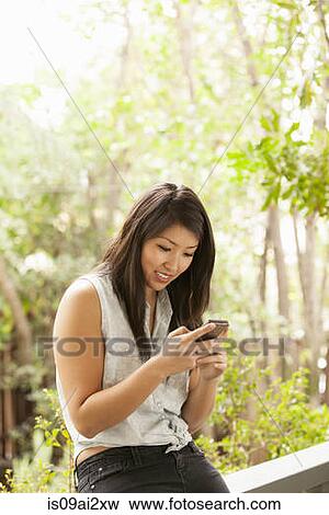 Young woman using smart phone on porch View Large Photo Image Stock Photo - Young woman using smart phone on porch. Fotosearch