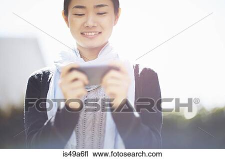Stock Image - Young woman using smartphone. Fotosearch