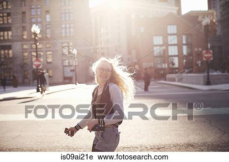 Young woman walking down street in Boston, carrying camera and smartphone View Large Photo Image Stock Image - Young woman walking down street in Boston, carrying camera and smartphone. Fotosearch