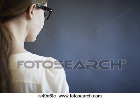 Stock Image - Young woman wearing glasses, studio shot. Fotosearch