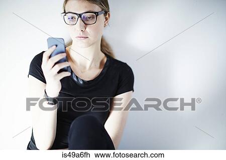 Young woman wearing glasses using smartphone View Large Photo Image Stock Image - Young woman wearing glasses using smartphone. Fotosearch