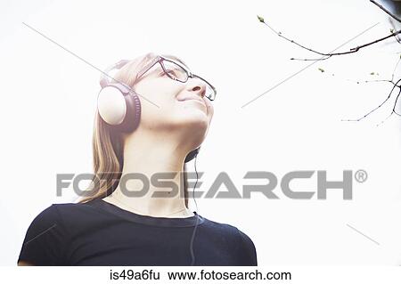 Young woman wearing headphones listening to music View Large Photo Image Stock Photograph - Young woman wearing headphones listening to music. Fotosearch