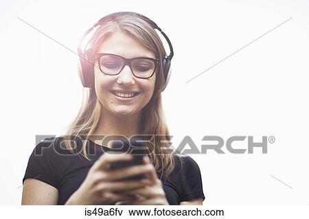 Young woman wearing headphones using smartphone View Large Photo Image Stock Photo - Young woman wearing headphones using smartphone. Fotosearch
