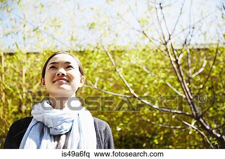 Stock Photography - Young woman wearing scarf looking up, smiling. Fotosearch