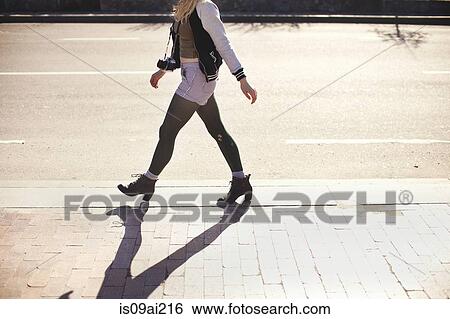 Stock Photograph - Young woman with camera walking down street. Fotosearch
