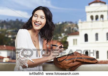 Young woman writing in notebook outdoors View Large Photo Image Stock Photography - Young woman writing in notebook outdoors. Fotosearch