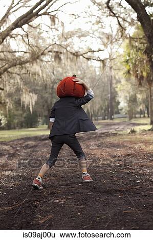 Boy running in forest holding onto pumpkin head View Large Photo Image Stock Photograph - Boy running in forest holding onto pumpkin head. Fotosearch