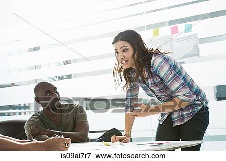 Businesswoman explaining ideas to male colleagues in office View Large Photo Image Stock Photo - Businesswoman explaining ideas to male colleagues in office. Fotosearch