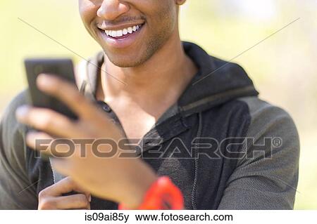 Stock Photo - Close up of young male hiker looking at smartphone. Fotosearch