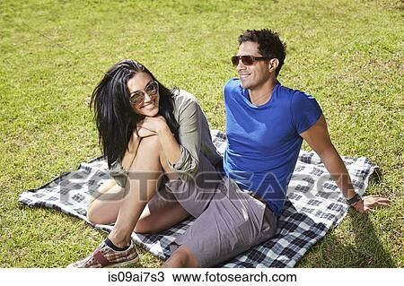 Couple sitting on picnic blanket in park View Large Photo Image Stock Image - Couple sitting on picnic blanket in park. Fotosearch