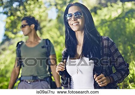 Stock Photograph - Couple walking with backpacks in forest. Fotosearch