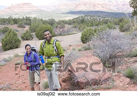 Stock Image - Couple with water bottles out hiking, Sedona, Arizona, USA. Fotosearch