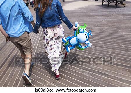 Picture - Cropped rear view of couple holding hands on boardwalk. Fotosearch