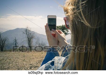 Cropped shot of mid adult woman photographing view on smartphone, Lake Arrowhead, California, USA View Large Photo Image Stock Photography - Cropped shot of mid adult woman photographing view on smartphone, Lake Arrowhead, California, USA. Fotosearch