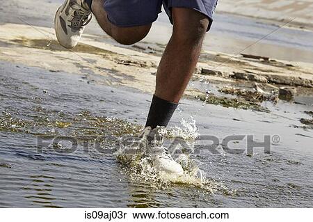 Cropped view of young man running through river View Large Photo Image Stock Photography - Cropped view of young man running through river. Fotosearch