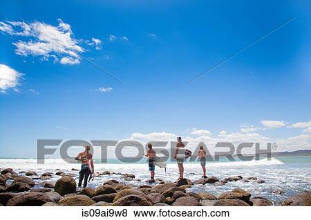 Four young male surfer friends watching sea View Large Photo Image Stock Photo - Four young male surfer friends watching sea. Fotosearch