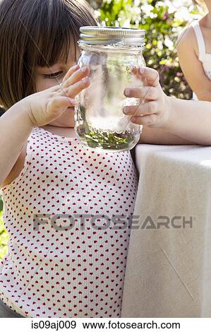 Stock Photo - Girl holding jar with green anole lizard in garden. Fotosearch