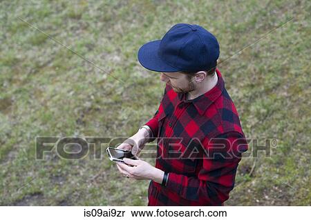 Stock Photography - High angle view of mid adult man texting on smartphone. Fotosearch