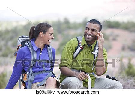 Stock Photo - Hiking couple chatting on smartphone, Sedona, Arizona, USA. Fotosearch
