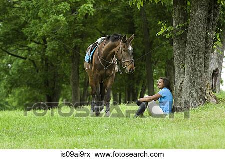 Horse rider sitting beside tree, horse beside View Large Photo Image Stock Photo - Horse rider sitting beside tree, horse beside. Fotosearch