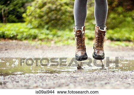 Picture - Legs and feet, jumping in puddle. Fotosearch