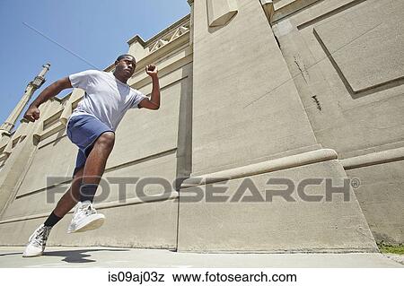 Stock Photo - Low angle view of young man speed running. Fotosearch