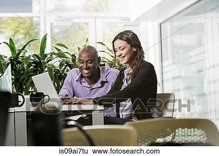 Male and female business colleagues using laptop in office View Large Photo Image Stock Photograph - Male and female business colleagues using laptop in office. Fotosearch