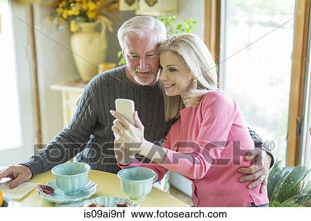 Stock Image - Mature couple reading text message on smartphone. Fotosearch