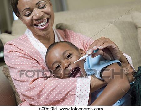 Mature mother taking reluctant temperature of reluctant son View Large Photo Image Stock Image - Mature mother taking reluctant temperature of reluctant son. Fotosearch