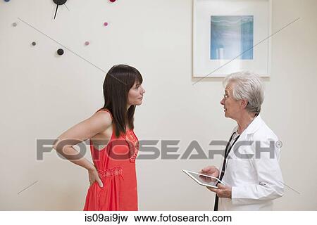 Stock Photo - Mature woman questioning female doctor face to face in doctors office. Fotosearch