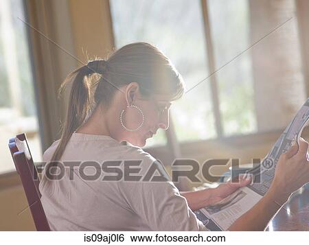 Mature woman reading newspaper in dining room View Large Photo Image Stock Photograph - Mature woman reading newspaper in dining room. Fotosearch