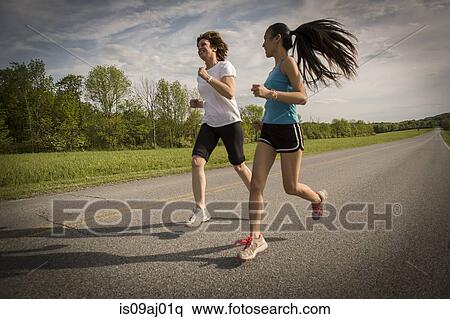 Mid adult woman and teenage girl running on road View Large Photo Image Stock Photography - Mid adult woman and teenage girl running on road. Fotosearch