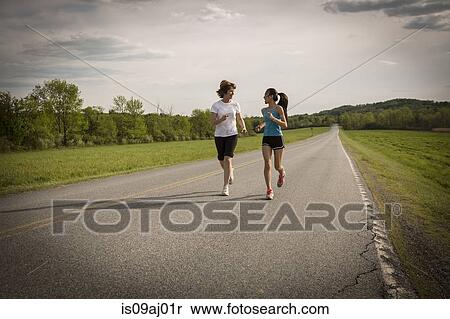 Mid adult woman and teenage girl running on road View Large Photo Image Stock Photography - Mid adult woman and teenage girl running on road. Fotosearch
