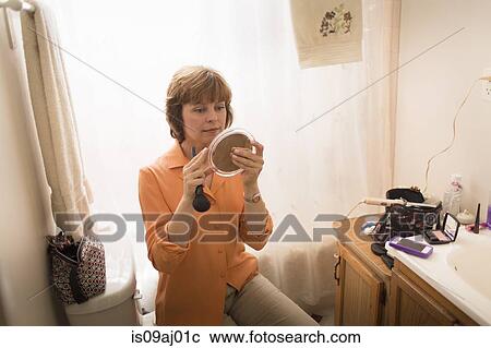 Stock Image - Mid adult woman applying make-up. Fotosearch