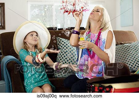 Mother and daughter blowing bubbles in sitting room View Large Photo Image Stock Photography - Mother and daughter blowing bubbles in sitting room. Fotosearch