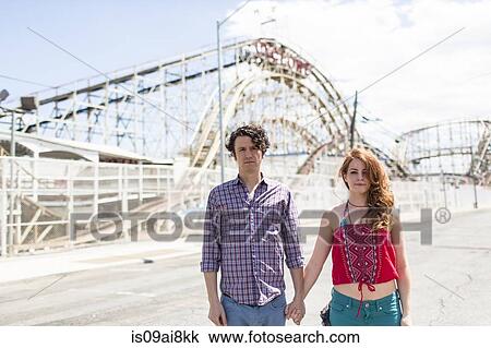 Stock Image - Portrait of couple with blank expressions at amusement park. Fotosearch