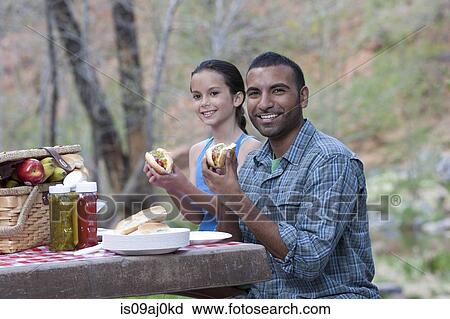 Stock Image - Portrait of father and daughter eating burgers whilst camping, Sedona, Arizona, USA. Fotosearch