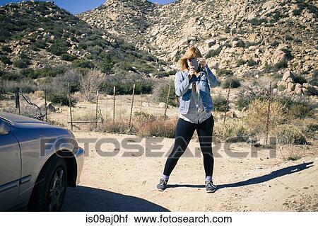 Portrait of mid adult woman on dirt track taking photograph on smartphone View Large Photo Image Stock Image - Portrait of mid adult woman on dirt track taking photograph on smartphone. Fotosearch