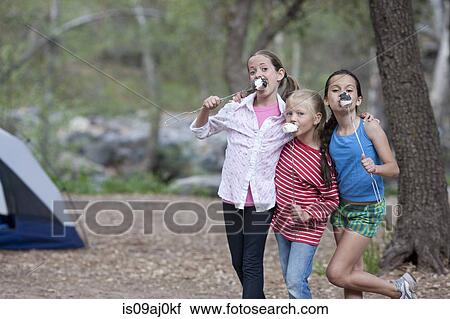 Stock Image - Portrait of three children eating toasted marshmallows whilst camping, Sedona, Arizona, USA. Fotosearch