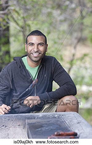 Portrait of young man grilling sausages on campsite, Sedona, Arizona, USA View Large Photo Image Stock Image - Portrait of young man grilling sausages on campsite, Sedona, Arizona, USA. Fotosearch