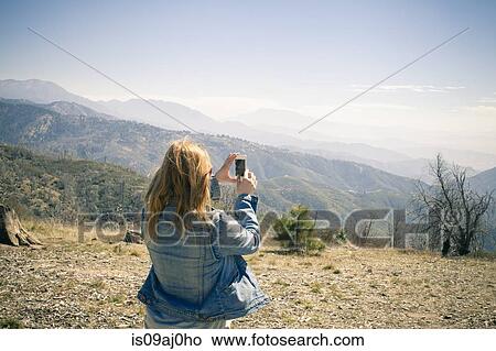 Rear view of mid adult woman photographing view on smartphone, Lake Arrowhead, California, USA View Large Photo Image Picture - Rear view of mid adult woman photographing view on smartphone, Lake Arrowhead, California, USA. Fotosearch