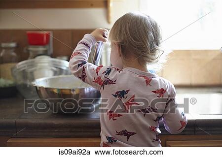 Stock Image - Rear view of toddler baking. Fotosearch