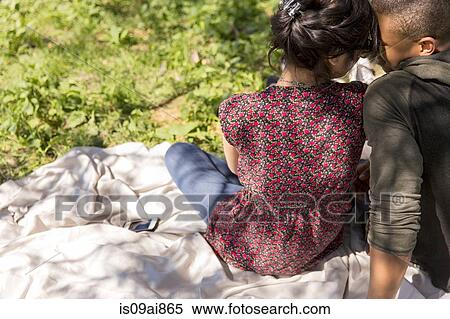Rear view of young couple sitting on picnic blanket View Large Photo Image Stock Photography - Rear view of young couple sitting on picnic blanket. Fotosearch