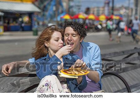 Romantic couple eating chips at amusement park View Large Photo Image Stock Photograph - Romantic couple eating chips at amusement park. Fotosearch
